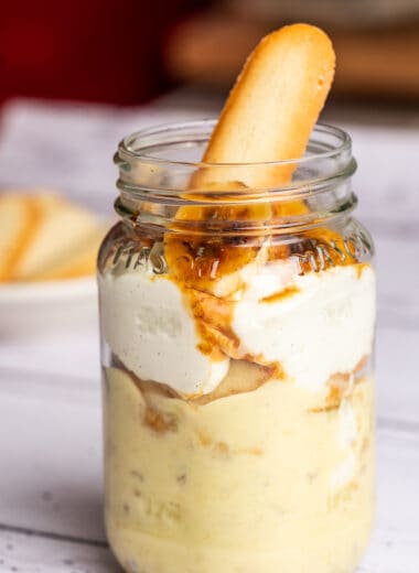 banana pudding in a mason jar, topped with caramelized bananas and cookies.